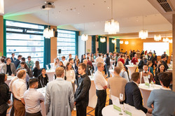 Das Bild zeigt den Saal des Westfälischen Industrieklubs, wo sich Studierende, Fördernde und Fakultätsangehörige an Stehtischen unterhalten. 