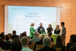 Blick aus den hinteren Publikumsreihen Richtung Bühnenbereich, wo Moderatorin Britt Lorenzen gerade eine Talkrunde mit vier Stipendiatinnen und Stipendiaten leitet