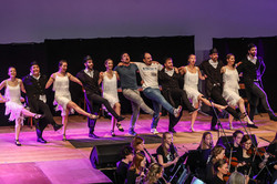 Eine Gruppe tanzt in einer Reihe auf der Bühne des Audimax.