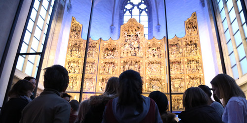 Kinder zu Besuch in der St. Petri Kirche bewundern den goldenen Altar 