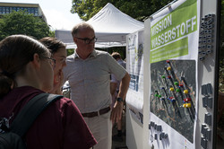 Zwei Besucherinnen schauen sich einen interaktiven Stand zum Thema Wasserstoff an.
