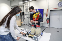 A woman and a man are standing around a table observing an experimental setup.