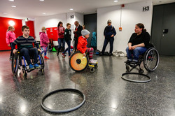 KinderUni-Rollen Zwei Kinder und eine Frau fahren im Rollstuhl.
