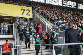 Eine Gruppe von Cheerleadern betritt die Tribüne eines mit Erstsemesterstudierenden gefüllten Fußballstadions.