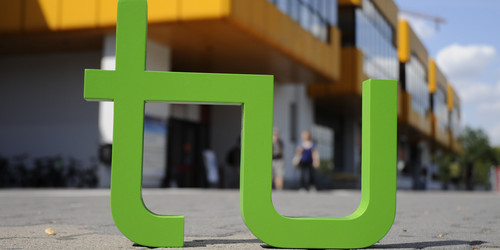 TU-Logo steht vor dem Mensagebäude
