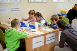 Vier Kinder sitzen an einem Tisch mit Utensilien und malen