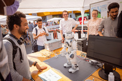 Summer festival 2022 Several people are standing around a table on which a soccer robot is placed.
