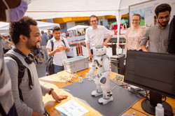 Several people are standing around a table on which a soccer robot is placed.