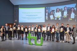 Dissertationspreisträger*innen stehen mit Urkunden auf der Bühne zusammen mit Rektor Bayer und Prorektorin Forschung McElvany