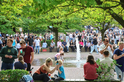 Photo of a fountain on the north campus of TU Dortmund University. Many people are sitting and standing around the fountain.