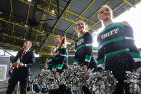 Eine Gruppe von Cheerleadern ist bereit für ihren Auftritt vor einer Tribüne gefüllt mit Erstsemesterstudierenden.
