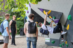 Photo: A student climbs on a boulder rock. Three other students watch him.