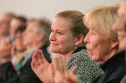 Teilnehmende der Stipendienfeier sitzen im Publikum und applaudieren