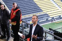 A man with a microphone in a stadium stand giving a speech. 