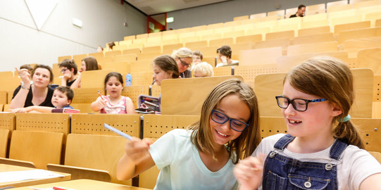 KinderUni-Hörsaal Kinder sitzen in den Reihen eines Hörsaals und bearbeiten Mathematikaufgaben mit Spaß und Spannung - Trickspiele