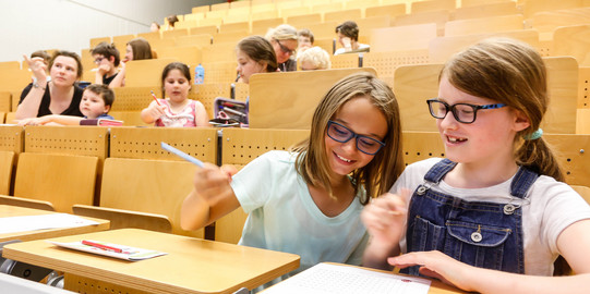 KinderUni-Hörsaal Kinder sitzen in den Reihen eines Hörsaals und bearbeiten Mathematikaufgaben mit Spaß und Spannung - Trickspiele