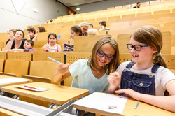 KinderUni-Hörsaal Kinder sitzen in den Reihen eines Hörsaals und bearbeiten Mathematikaufgaben mit Spaß und Spannung - Trickspiele