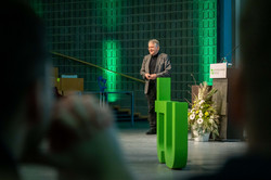 Prof. Dr. Klaus von Klitzing in the green-lit Audimax. The green TU logo in the foreground.