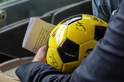 A black and yellow soccer lies on the lap of a person.
