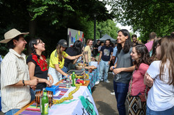 Photo: Several people stand at an international stand and talk to the people at the stand.