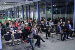 Foto: Mehrere Personen sitzen in Reihen und folgen einer Veranstaltung.
