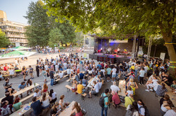 Summer festival 2022 In front of a music stage, many people are gathered standing and sitting on beer tent benches.