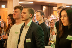 Stipendiatinnen und Stipendiaten blicken Richtung Bühnenbereich und verfolgen das Programm der Feier
