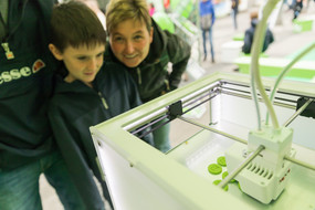 Mother with son watching 3D printer in action