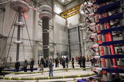 Menschen laufen zwischen großen Metallapparaten in einer Experimentierhalle.