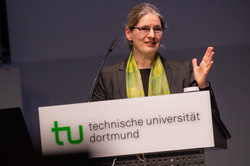 Das Bild zeigt Prof. Barbara Hammer, Professorin für Machine Learning an der Universität Bielefeld, hinter einem Pult mit TU-Dortmund-Schild.