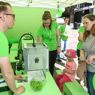 Besucher am TU Dortmund Stand mit 3D Drucker für Schlüsselanhänger