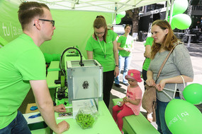 Visitors at TU Dortmund stand with 3D printer for key rings
