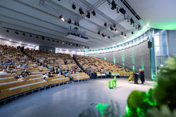 Foto: Blick in einen großen Hörsaal der Technischen Universität Dortmund, in dem zahlreiche Personen einer Präsentation folgen.