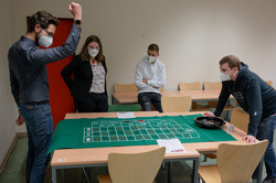 Four people stand around a table and play a game
