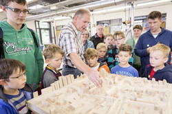 KinderUni-Modellbau Kinder und Erwachsene stehen rund um ein Modell einer Stadt.