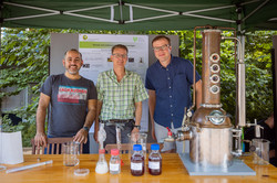 Summer festival 2022 Three men stand side by side behind a stand.