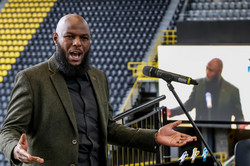 A singer standing in front of a microphone in the stands of the BVB stadium.