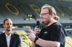 A representative of the AstA holding a microphone. Next to him is a man in a suit. The two of them are standing in the stands of the BVB stadium.