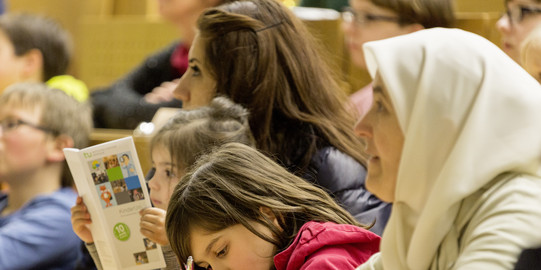 KinderUni Kinder und Eltern internationaler Herkunft lauschen der Vorlesung im Hörsaal