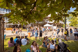 Summer festival 2022 Visitors of a summer festival sit in the shade and cavort in front of booths.